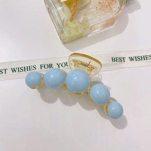 Detailed close-up of blue acrylic pearl hair claw clip with golden spring mechanism