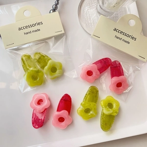 Close-up of translucent resin flower hair clips in pink and green on a white tray