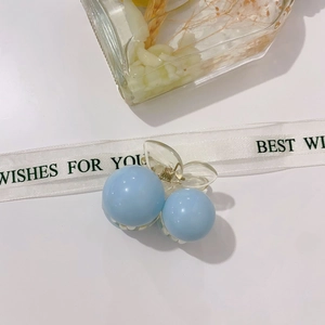 Detailed view of sky blue cherry-shaped acrylic hair claw clip with golden metal spring