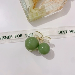 Detailed close-up of bean green acrylic hair claw with gold spring on white surface