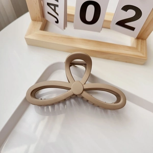Macro detail of matte milk tea colored flower hair claw clip with cutout petals