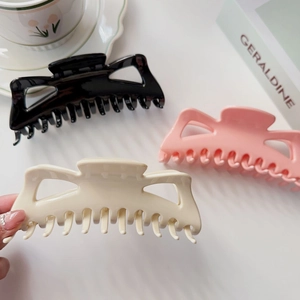 Vue détaillée de grandes pinces à cheveux crème, roses et noires dans un cadre cosy