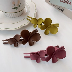 Détail de pinces à cheveux papillon mates en jaune moutarde, marron et rose poudré
