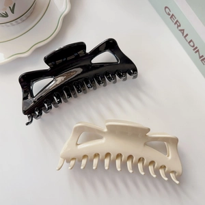 Grandes pinces à cheveux crème et noires pour cheveux épais sur fond esthétique