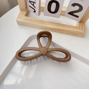 Detail view of large matte coffee brown hair claw clip on a minimalist white tray