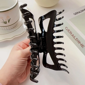 Gros plan sur la grande pince à cheveux papillon noire brillante au design ajouré