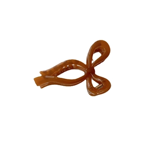 Brown amber-style jelly resin bow hair claw clip with golden metal spring on white background