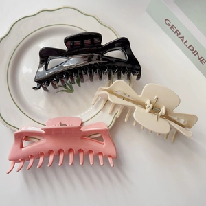 Gros plan de grandes pinces à cheveux crème, noires et roses sur une assiette décorative