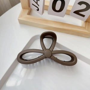 Detailed view of large dark brown matte hair claw clip on a minimalist white tray
