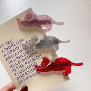 Detail of three acrylic cat-shaped hair clips in pink, marble grey, and red glitter