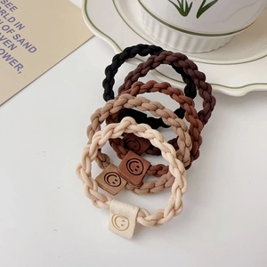 Macro detail of elastic twisted hair ties with leather smiley face charms in earth tones