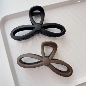 Detail of matte black and coffee brown large bow hair claws in a minimalist tray