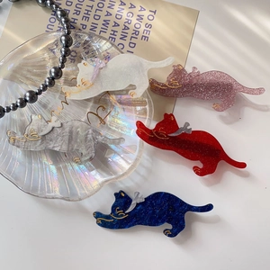 Flat lay of five colorful cat-shaped hair clips in various patterns on a shell tray