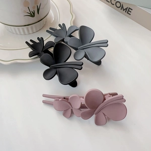 Détail de pinces à cheveux papillon mates noires, grises et roses sur une table
