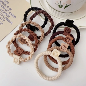 Detailed view of elastic twisted hair ties with smiley face charms in earth tones