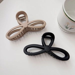 Detail view of matte finish hair claw clips in beige and black with triple loop design