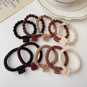 Detail view of 10 elastic twisted hair ties in earth tones with a smile face label