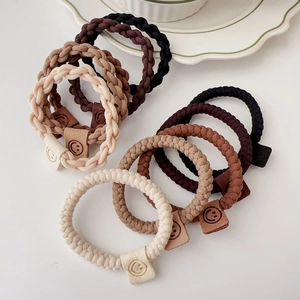 Detail of durable braided hair ties in earth tones with small smile pattern tags