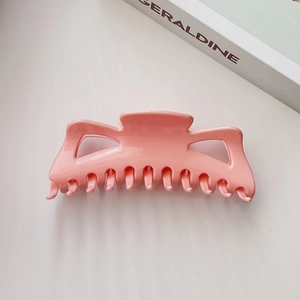 Gros plan sur la grande pince à cheveux rose mat avec de longues dents pour cheveux épais