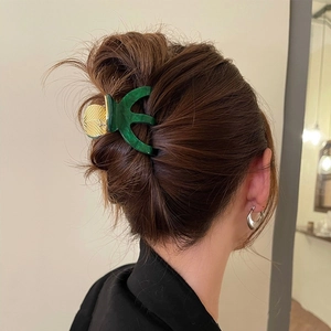 Green marble acetate hair claw clip with golden leaf accents on wavy brown hair
