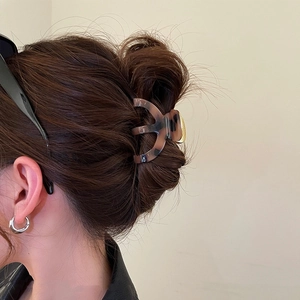 Detail view of large tortoise shell hair claw clip with gold accent on dark hair
