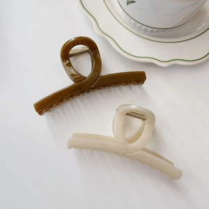 Dettaglio di fermagli per capelli in resina verde oliva e beige crema dal design geometrico