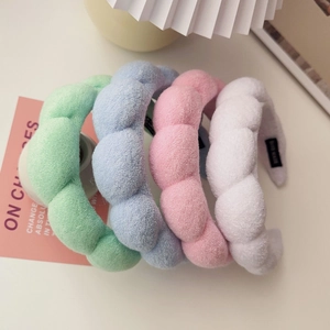Close-up of assorted plush sponge headbands in mint, blue, pink, and white fabrics