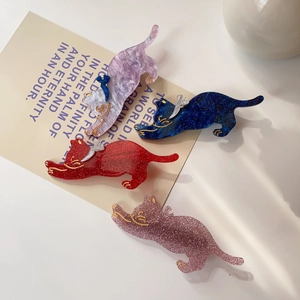 Close-up of four colorful cat hair clips with marble texture on an artistic card