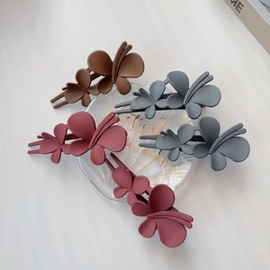 Détail de quatre pinces à cheveux papillon mates aux tons marron et bordeaux élégants