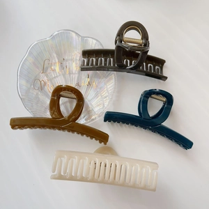 Dettaglio di grandi mollette per capelli in resina nei colori oliva, blu, ambra e crema