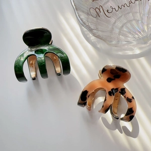 Close-up of green marble and leopard print hair claws with elegant metal spring detail