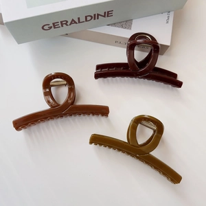 Tre grandi mollette per capelli in tartaruga marrone e verde su un libro di design