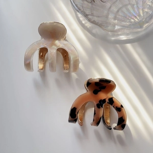 Macro detail of mother-of-pearl and tortoiseshell acetate hair claws with gold-tone metal hinges