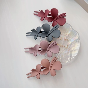 Gros plan de pinces à cheveux papillon mates en quatre couleurs avec design d'ailes superposées