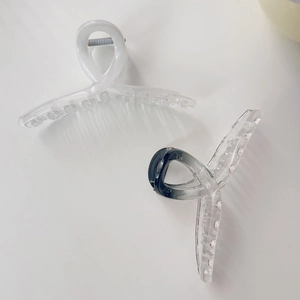 Detail view of large matte white and black gradient hair claws with metal spring