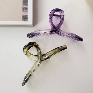 Close-up of large translucent purple and tortoiseshell hair claws on white surface