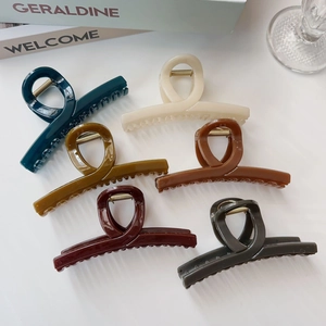 Set di sei pinze per capelli in resina lucida in vari colori su sfondo di una rivista