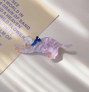 Detailed macro view of purple marble texture acrylic cat hair clip with blue bow detail