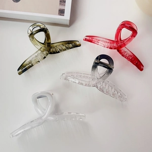 Macro detail of large hair claw clips in olive green and red resin on neutral background