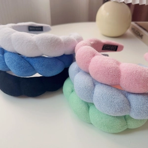 Close-up of six colorful twisted sponge headbands with soft braided texture on a white table