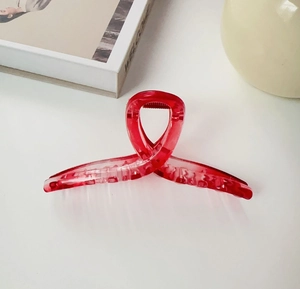 Detail view of large red translucent shark hair claw clip in elegant ribbon shape design