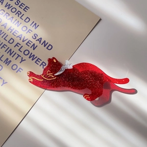 Close-up of a red glitter cat hair clip with a silver bow and elegant shadow lighting