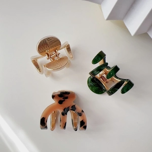 Detailed set of three acetate shark hair clips in beige, green, and tortoiseshell patterns