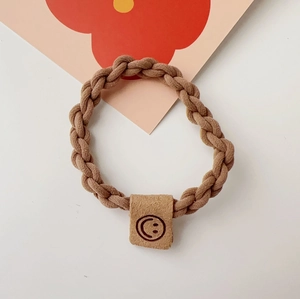 Detailed view of durable brown braided hair tie with a cute smiley face leather tag