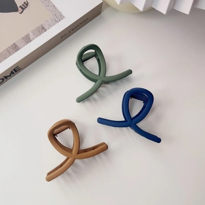 Gros plan sur des pinces à cheveux mates en vert foncé, bleu marine et caramel