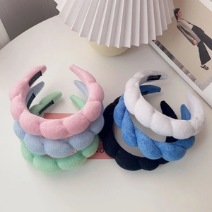 Detail view of twisted sponge headbands in multiple pastel colors with handmade labels