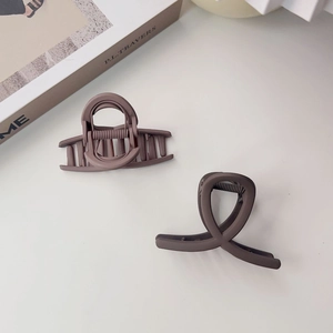 Gros plan de pinces à cheveux marron mat au design minimaliste croisé et incurvé