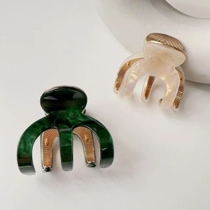 Detailed close-up of marble pattern acetate hair claws in dark green and pearl white