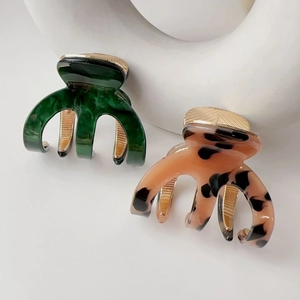 Detail of marble pattern acetate claw clips in dark green and leopard print with gold clips