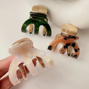 Detailed view of three acetate hair claws in marble, tortoiseshell, and pearl white colors